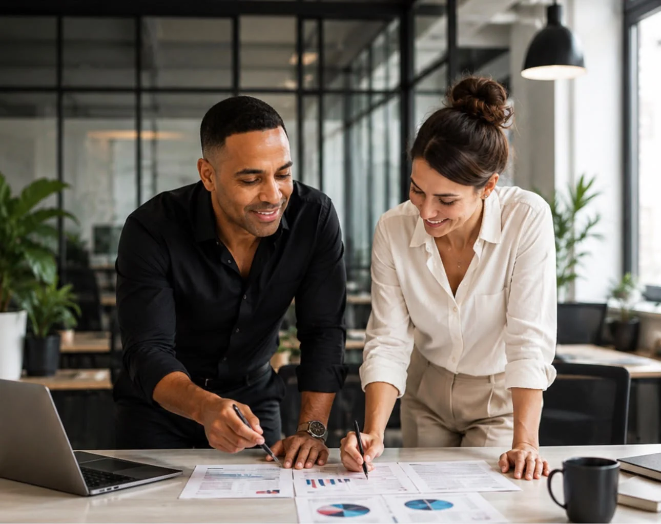 Two business professionals reviewing workforce documents and charts together in a modern office
